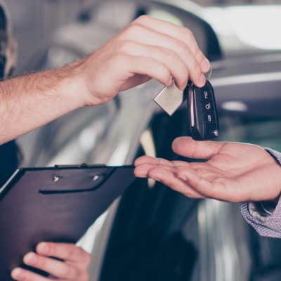 Closeup of mechanic handing keys to businessman
