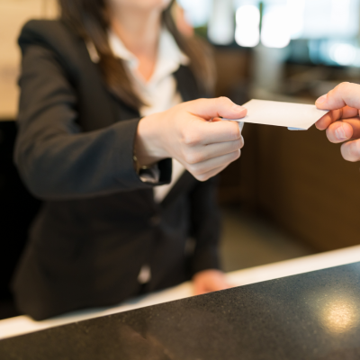 Front desk receptionist handing key to hotel guest