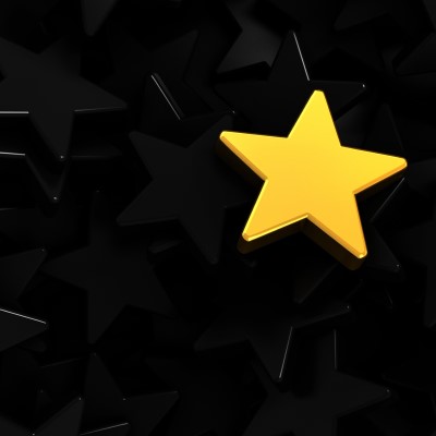 Single yellow star against background of black stars