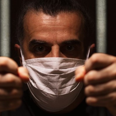 Masked man looking through bars