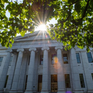 Sun filtering through trees onto government building with majestic columns