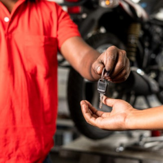 Motorbike mechanic handing over keys to customer