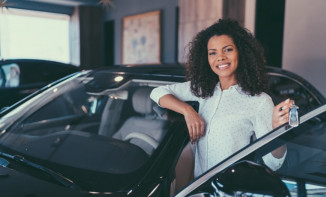 Woman standing next to new car holding keys