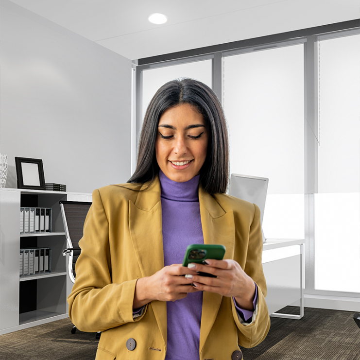 Professional woman standing in office looking at phone